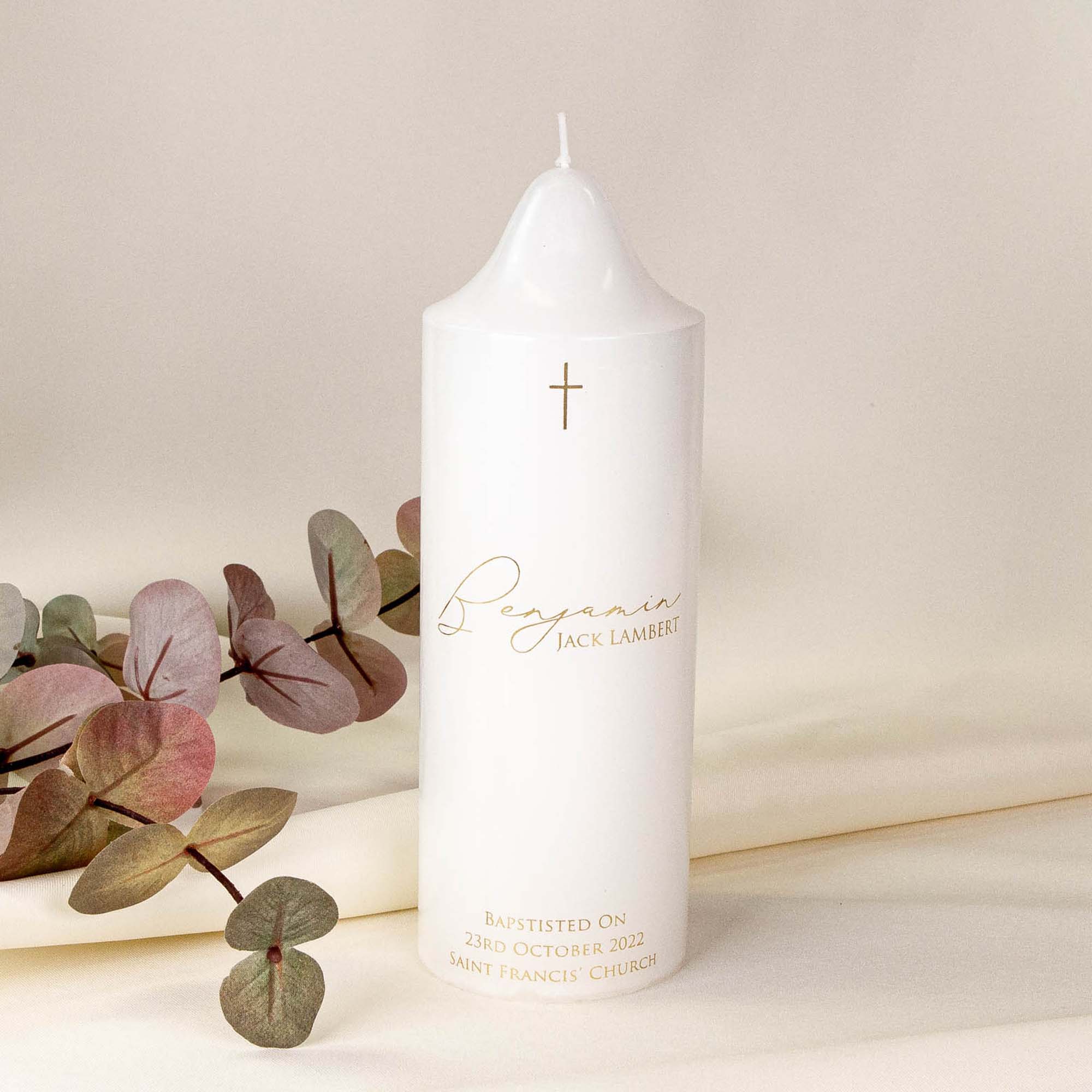 Personalised white baptism candle in gold text as "Benjamin JACK LAMBERT" as the name and his baptism date also on it.